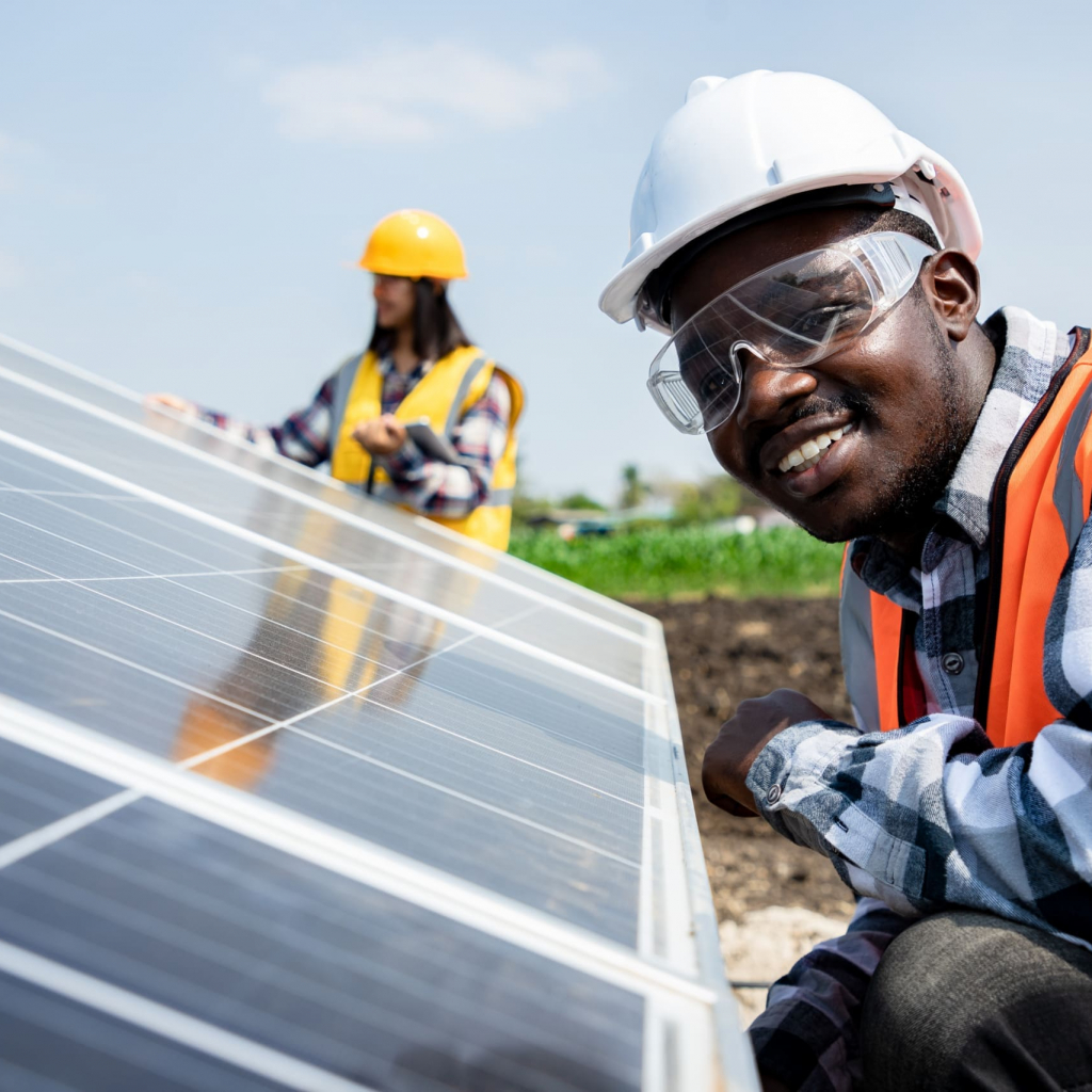 Two workers technicians installing heavy solar photo voltaic panels to high steel platform in corn field. Photovoltaic module idea for clean energy. Green energy concept